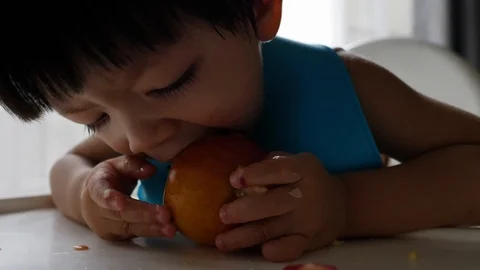 First time, cute child eating bite a apple Stock Footage 92637837