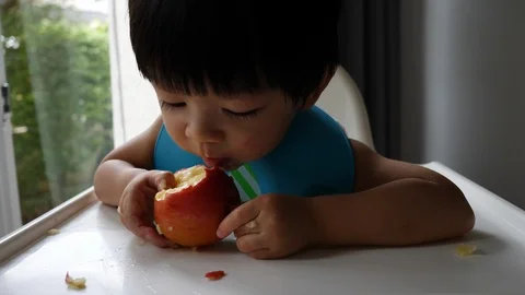 First time, cute child eating bite a apple Stock Footage 93889526