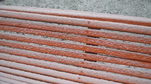 The first white snow covered an orange bench in the park. Snowy cold winter Video stock 83394386