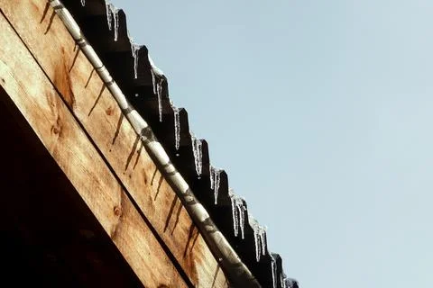 First winter icicles dripping droplets with a wavy roof hemmed wooden planks Stock Photos