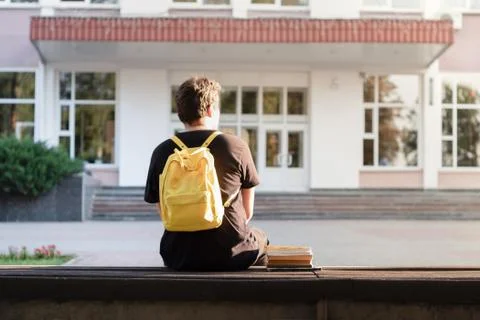First year student sitting outside a university or school facility.  Stock Photos