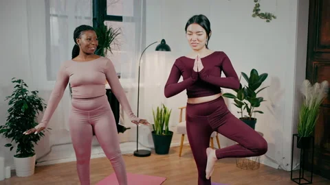 First yoga training. Professional black woman coach showing asian lady basic Video stock 170577247