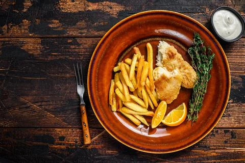Fish and Chips british fast food with french fries and tartar sauce on a rustic Stock Photos