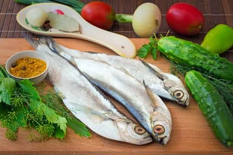 Fish and components for her preparation: vegetables, spices, parsley. Stock Photos