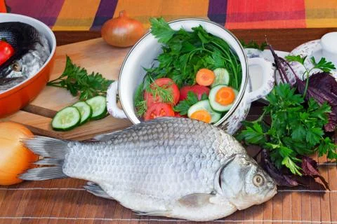 Fish and components for her preparation: vegetables, spices, parsley. Stock Photos