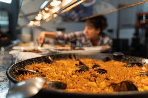 Fish-based dish at a self-service food counter with an unfocused girl in the  Stock Photos