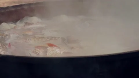 Fish is being boiled in black pot on fire. Side view of smoke and meals. Stock Footage 144454332