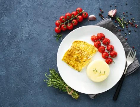 Fish cod baked in oven with mashed potatoes, tomatoes, diet healthy food. Dark Stock Photos