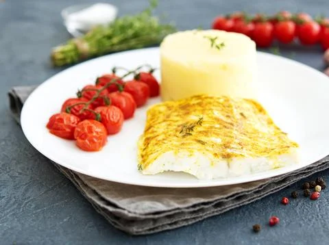 Fish cod baked in oven with mashed potatoes, tomatoes, diet healthy food. D.. Stock Photos