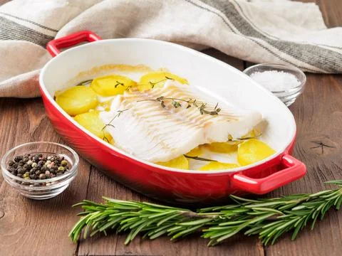 Fish cod baked in the oven with potatoes and spice and thyme - healthy diet.. Stock Photos