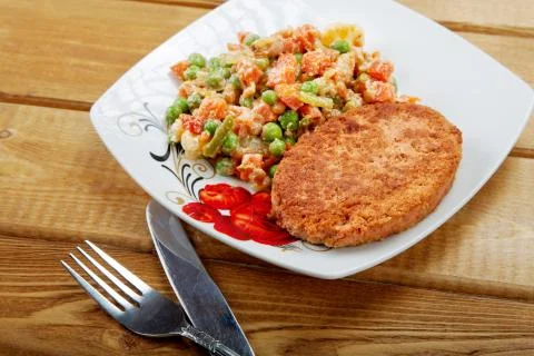 Fish cutlet with a vegetable garnish on a table Stock Photos