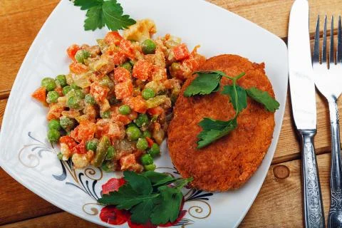 Fish cutlet with a vegetable garnish on a table Stock Photos