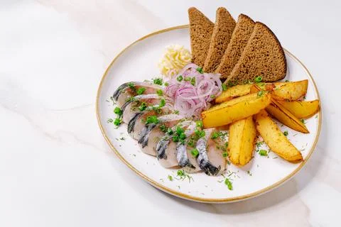 Fish dish with bread and potatoes served on a white plate Stock Photos