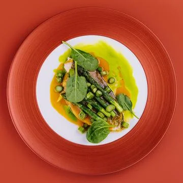 Fish dish - fried cod fillet with asparagus and basil served on red plate Stock Photos