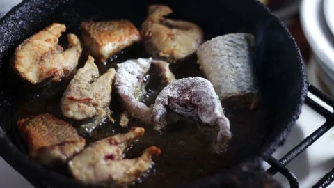 Fish fried in a frying pan until golden brown Stock Footage