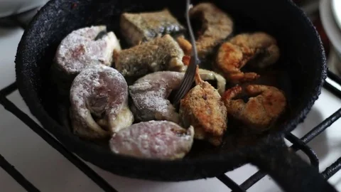 Fish fried in a pan turned with a fork Stock Footage