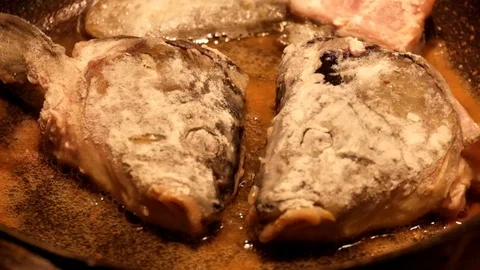 Fish heads breaded in flour are fried in oil in a frying pan Stock Footage 89136394