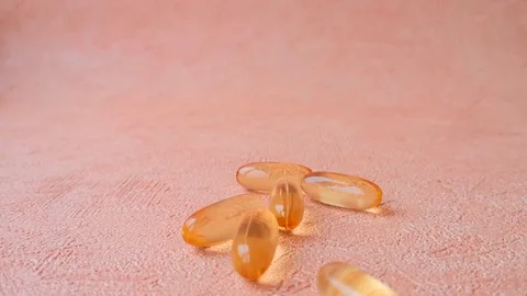 Fish oil pills fall to the surface Stock Footage 103857722