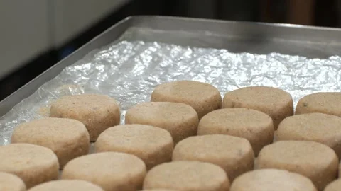 Fish patties put on tinfoil-lined tray while cook lightly presses with spatula Video stock 329434224