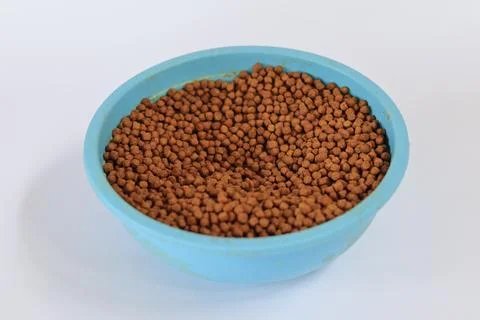 Fish pellets in container isolated on white background. Stock Photos