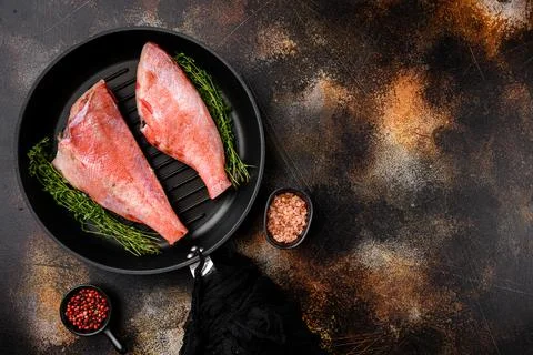 Fish raw snapper, in frying cast iron pan, on old dark rustic table background Stock Photos