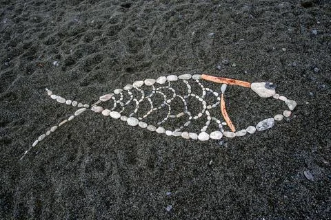 Fish Shape Made of Stones on Dark Sand Stock Photos