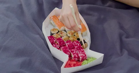 A fish-shaped box full of various sushi, placed on a blue blanket in the woods Stock Footage 202197861