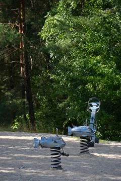 Fish Shaped Spring Riders on an Empty Sandy Playground Surrounded by Forest Stock Photos