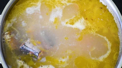 Fish soup boiling in a metal pot on a black tile panels background Video stock 104175331