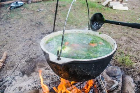 Fish soup cooking in a pot on a fire in the forest by the sea Stock Photos