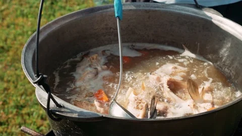 Fish soup is prepared on fire in a cauldron outdoors. Fish soup on fire Stock Footage 200449834