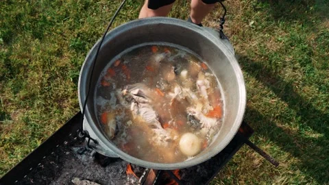 Fish soup is prepared on fire in a cauldron outdoors. Fish soup on fire Stock Footage 200451443