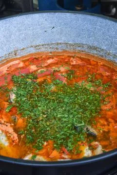 Fish stew being cooked boiling in traditional large pan Foto stock
