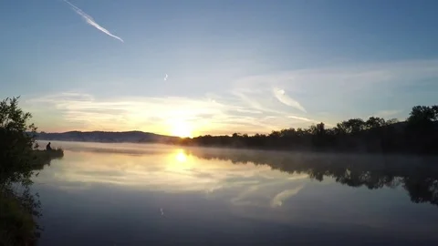 Fisherman and moving fog over the lake at dawn Stock Footage 76001053