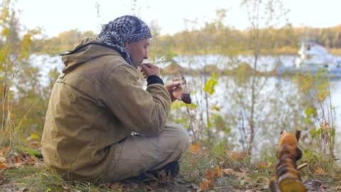 A fisherman on the bank of the river eats fish Stock Footage 87952227