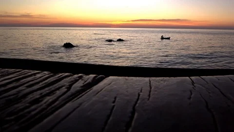 Fisherman in the boat on pink sunset background. Old wooden surface. Video Stockbeeldmateriaal 123778252