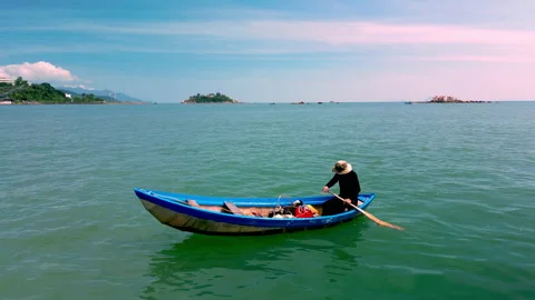 A fisherman on a boat rows with oars after fishing, he swims to the shore home Stock Footage 234828892