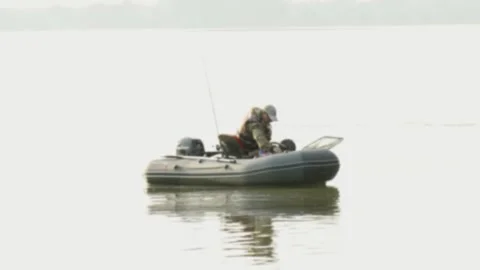 Fisherman in a cap sitting inside inflatable boat on river Stock Footage 337754242