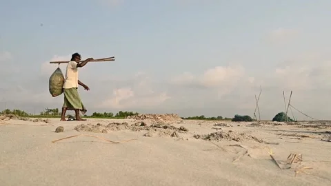 Fisherman Carrying Heavy Load on Shoulder Across Sandy sea beach Area Stock Footage 239170296