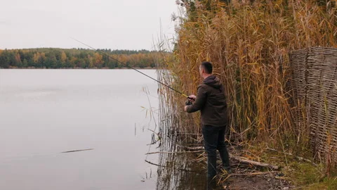 Fisherman casting spinning rod while predator fishing, man standing near reeds Stock Footage 320143231