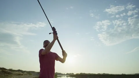 A fisherman casts a spinning reel in the rays of the morning sun. Video stock 245750738