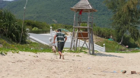 Fisherman with a catch walking on a beach. Man taking away a few small stingrays Stockbeeldmateriaal 62616439