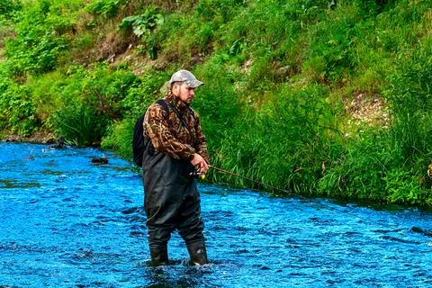 A fisherman catches fish while standing in the water Stock Photos