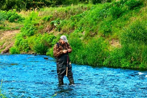 A fisherman catches fish while standing in the water Stock Photos