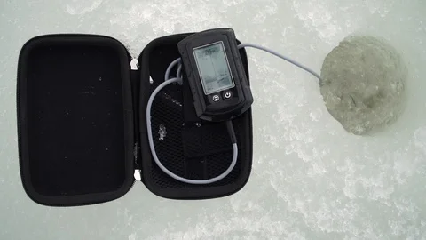 Fisherman catches fish with a winter echo sounder in a hole in a river Video stock 105210802