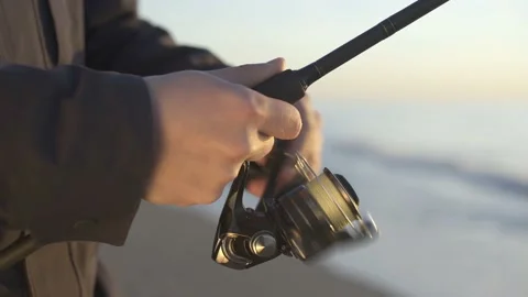 Fisherman catching fish by spinning on the beach. Close-up Stock Footage 239893360