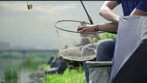 Fisherman caught wild fish on the river in the city. Fisherman takes the hook Stock Footage 78338360