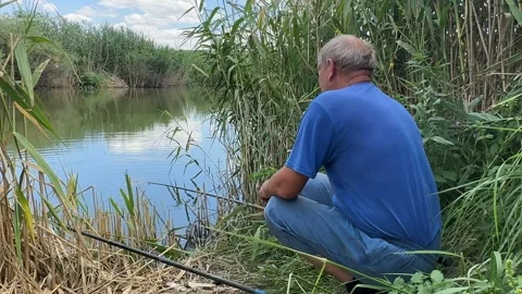 Fisherman an elderly retired man throws a fishing rod, catches fish in a pond.  Stock Footage 245107034