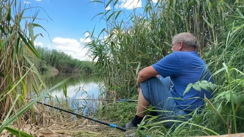 Fisherman an elderly retired man throws a fishing rod, catches fish in a pond. S Stock Footage 245107147