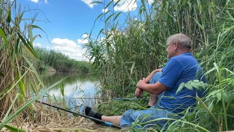 Fisherman an elderly retired man throws a fishing rod, catches fish in a pond.  Stock Footage 245107170